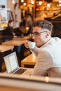 Attractive young man sitting in cafe while drinking coffee. Royalty Free Stock Photo