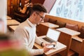 Attractive young man sitting in cafe while using smartphone. Royalty Free Stock Photo