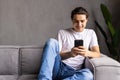 Attractive young man sitting on a floor in the living room, using mobile phone Royalty Free Stock Photo
