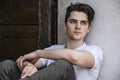 Attractive young man sitting on old door's threshold