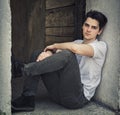 Attractive young man sitting on old door's threshold