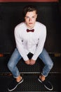 Attractive young man sitting on the stairs inside the pub.