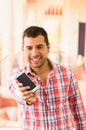 Attractive young man smiling holding a smartphone