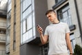 Attractive young man is standing on the street with a phone in his hands. Business handsome guy with a stylish hairstyle Royalty Free Stock Photo