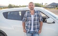 An attractive young man stands near a car. Royalty Free Stock Photo