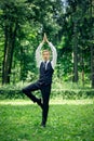 Attractive young man in a suit does yoga tree pose in a park Royalty Free Stock Photo