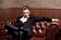 Attractive young man in a suit sitting on couch