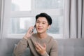 Attractive young man is talking on the mobile phone and smiling while sitting on sofa at home Royalty Free Stock Photo