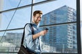 Attractive young man walking and looking at mobile phone Royalty Free Stock Photo