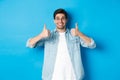 Attractive young man wearing glasses and casual clothes, showing thumbs up in approval, like something, standing against Royalty Free Stock Photo