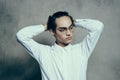 attractive young man wearing glasses white shirt straightens hair on his head portrait Royalty Free Stock Photo