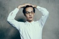 attractive young man wearing glasses white shirt straightens hair on his head portrait Royalty Free Stock Photo