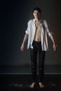 Attractive young man in white wet clothes in small pool under drops of the rain. Studio photo Royalty Free Stock Photo