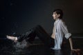 Attractive young man in white wet clothes in small pool under drops of the rain. Studio photo Royalty Free Stock Photo