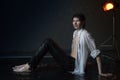 Attractive young man in white wet clothes in small pool under drops of the rain. Studio photo Royalty Free Stock Photo