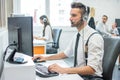 Attractive young man working in a call center with his colleagues. Royalty Free Stock Photo