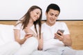 Young married couple sitting on sofa and watching video on the smartphone Royalty Free Stock Photo