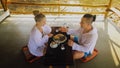 Man and woman eat and drink tasty beverages spending time in traditional local floating cafe on water. Loving happy