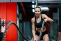 An attractive young muscular girl using training ropes for battle ropes exercise in a gym Royalty Free Stock Photo