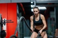 An attractive young muscular girl using training ropes for battle ropes exercise in a gym Royalty Free Stock Photo