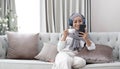 Attractive young Muslim woman sitting in living room, using smartphone and laptop computer. cropped image Royalty Free Stock Photo
