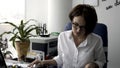 Attractive young office woman in white shirt working on the business papers near green plant and printer. Female office Royalty Free Stock Photo