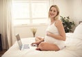 Attractive young pregnant woman with laptop on bed Royalty Free Stock Photo