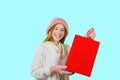 Attractive young red-haired girl with gift bags after shopping on a blue background looking towards the camera Royalty Free Stock Photo