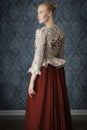 Red-haired 18th century woman standing in front of baroque wall paper Royalty Free Stock Photo
