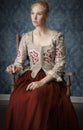 Red-haired 18th century woman standing in front of baroque wall paper Royalty Free Stock Photo