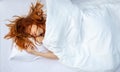 Attractive, young, sexy, red-haired woman, hair wild on the sheets, mouth open, lying in fresh soft white sheets in bedroom Royalty Free Stock Photo