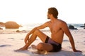 Attractive young shirtless man sitting on beach looking away