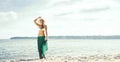 Beautiful, young woman wearing alluring bikini and green silk on the beach. Traveling, vacation, holiday, concept.