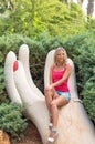 Attractive young smiling beautiful curly blonde hair slim girl fashion portrait in pink T-shirt posing looking away calm look, in Royalty Free Stock Photo