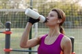 Attractive young swart woman in bright sportswear drinks water during fitness on outdoors sportsground. Active lifestyle woman hyd Royalty Free Stock Photo