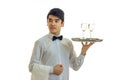 Attractive young waiter in a shirt raised in hand a tray with glasses