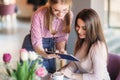 Attractive young waitress using a tablet computer to take an order from a customer in a coffee shop Royalty Free Stock Photo