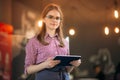 Attractive young waitress using a tablet computer to take an order from a customer in a coffee shop Royalty Free Stock Photo