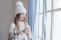 Attractive young winter woman holding hot dring and resting at home, romantic portrait