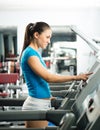 Attractive young woman adjusts the treadmill Royalty Free Stock Photo