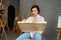 Attractive young woman artist holding canvas in hand drawing picture Royalty Free Stock Photo