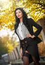 Attractive young woman in a autumnal fashion shot. Beautiful fashionable lady in black and white outfit posing in park Royalty Free Stock Photo