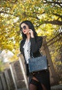 Attractive young woman in a autumnal fashion shot. Beautiful fashionable lady in black and white outfit posing in park Royalty Free Stock Photo