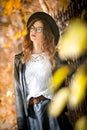 Attractive young woman in an autumnal shot outdoors. Beautiful fashionable school girl posing in park with faded leaves around