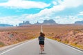 Attractive young woman from back view running in the middle of American straight road in the desert. Royalty Free Stock Photo
