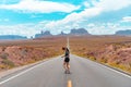 Attractive young woman from back view running in the middle of American straight road in the desert. Royalty Free Stock Photo