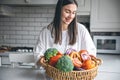 Attractive young woman and a basket of fruits and vegetables in the kitchen. Royalty Free Stock Photo