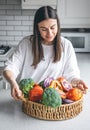 Attractive young woman and a basket of fruits and vegetables in the kitchen. Royalty Free Stock Photo