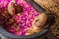 Attractive Young woman in bath with petals of tropical flowers and aroma oils. Spa treatments for skin rejuvenation