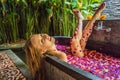 Attractive Young woman in bath with petals of tropical flowers and aroma oils. Spa treatments for skin rejuvenation